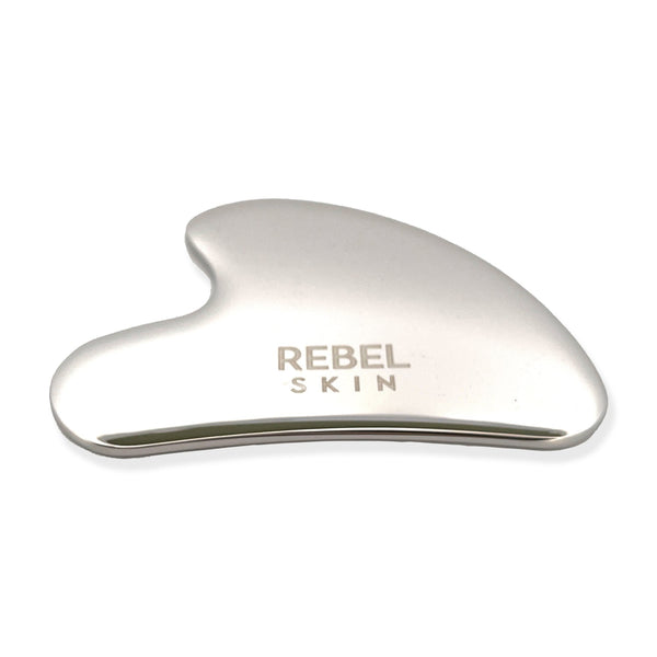 Heart-shaped REBEL SMOOTH Gua Sha tool in stainless steel for facial massage and contouring.